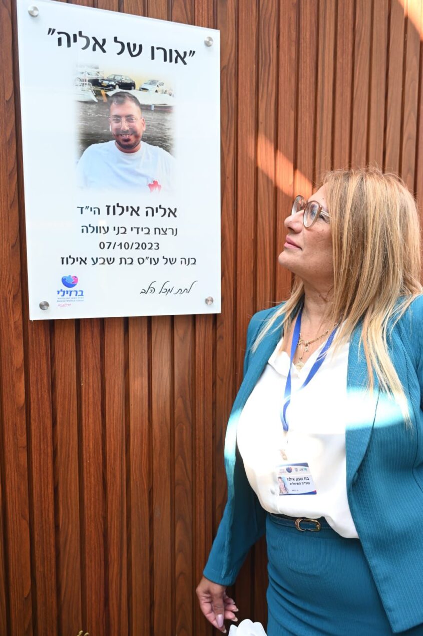 בת שבע אילוז, לצד תמונתו של אליה ז"ל, בטקס חניכת מרכז 'אורו של אליה' בבה"ח ברזילי